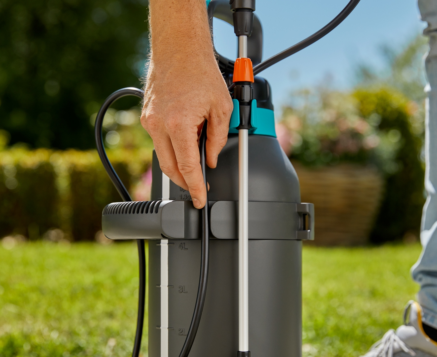 A person adjusting a garden sprayer in a sunny garden setting.
