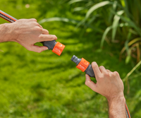 Two hands connecting Gardena hose connectors in a garden setting., miniatuur 2