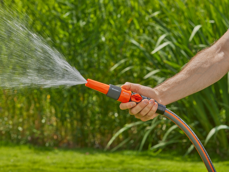 A person watering a garden with a hose nozzle, spraying water onto plants., afbeelding 3 Filterpomp