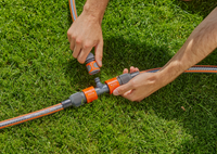 Hands connecting Gardena hose fittings on a grassy lawn., miniatuur 2