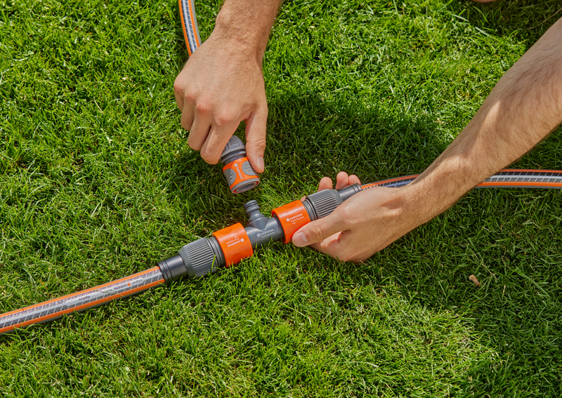 Hands connecting Gardena hose fittings on a grassy lawn., detailaanzicht Filterpomp
