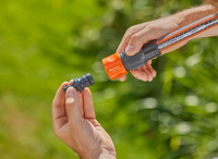 Hands connecting a Gardena hose fitting in a garden setting., miniatuur 2